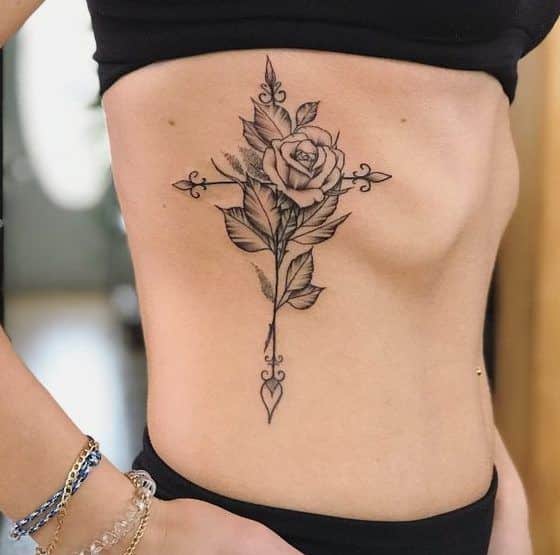 Tatuagem feminina de rosa com cruz na costela site tattooandyou.com